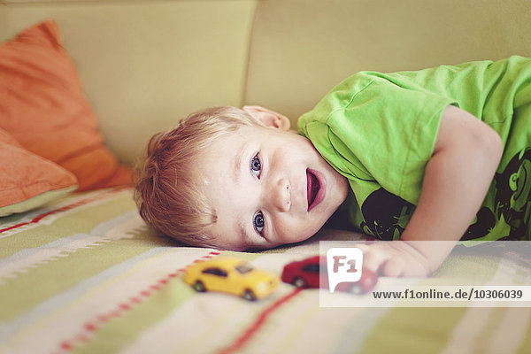 Porträt des glücklichen kleinen Jungen auf der Couch liegend