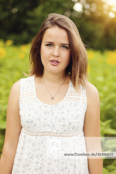 Portrait of young woman wearing summer dress standing in sunflower field