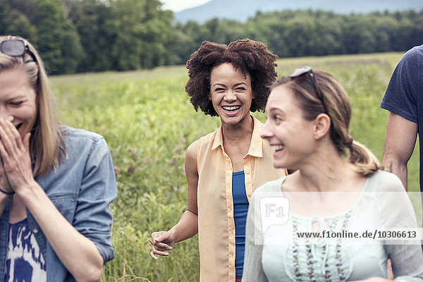 Eine Gruppe von Frauen geht lachend über eine Wiese auf dem Land.