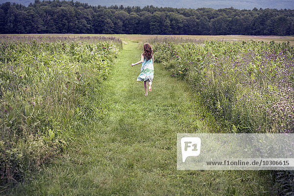 A girl running through a meadow in summer.