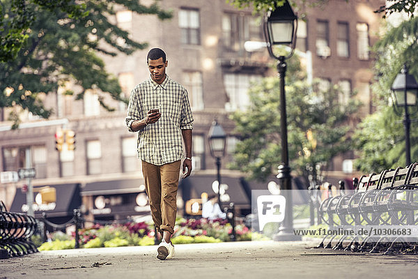 A man walking through a town square looking at his smart phone