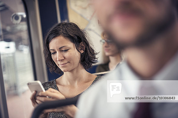 A woman on a bus looking down at her cell phone