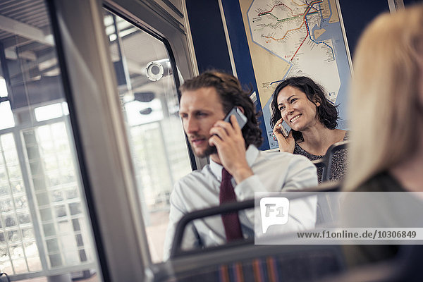 Zwei Personen  die in einem Bus sitzen und mit ihren Handys telefonieren