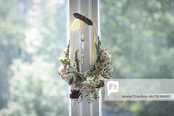 Self-made floral wreath hanging at window catch