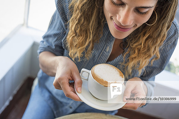 Eine Frau  die in einem Café eine Kaffeetasse hält.