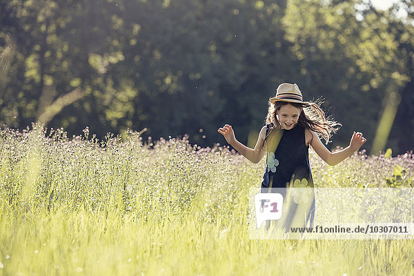 A child  a young girl in straw hat in a meadow of wild flowers in summer.