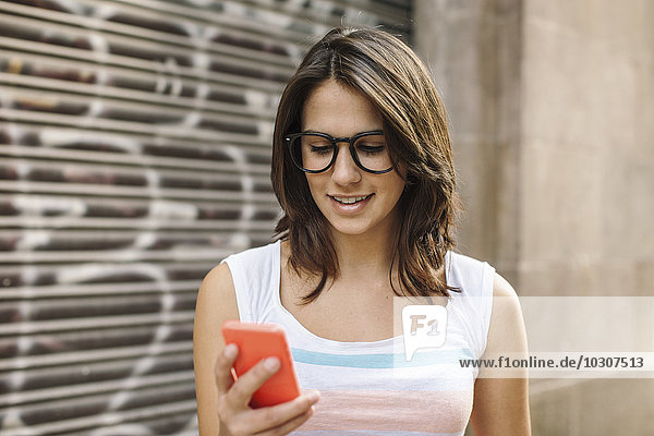 Lächelnde junge Frau mit Smartphone Lesung SMS