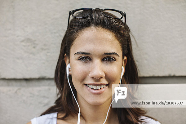 Porträt einer lächelnden jungen Frau mit Ohrhörern