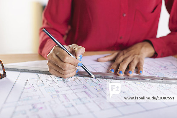 Hands of young female architect working on construction plan