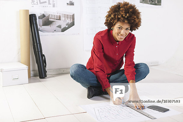 Young female architect working on the floor of her office