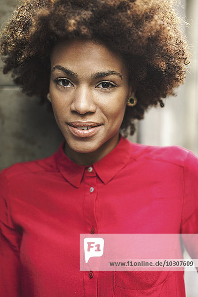 Porträt einer lächelnden jungen Frau in roter Bluse