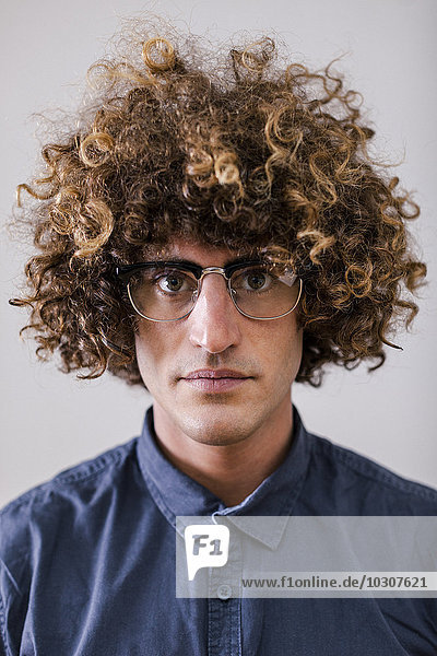 Portrait of serious looking man with curly hair wearing glasses