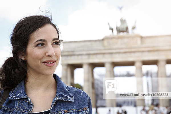Deutschland  Berlin  Portrait einer jungen Touristin auf Städtereise vor dem Brandenburger Tor