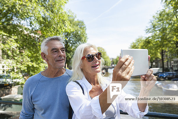 Netherlands  Amsterdam  senior couple taking a selfie at town canal