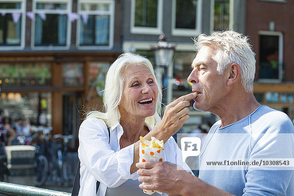 Netherlands  Amsterdam  happy senior couple eating French Fries
