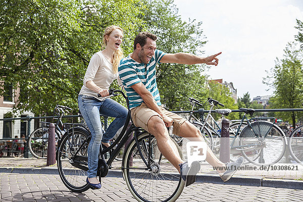 Netherlands  Amsterdam  happy couple riding bicycle in the city