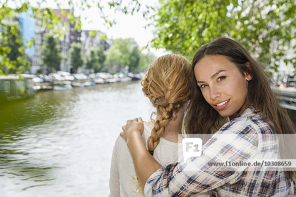 Netherlands  Amsterdam  two women embracing at town canal