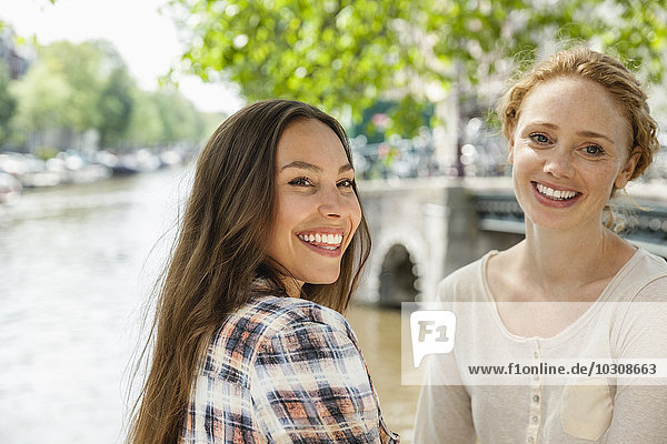Netherlands  Amsterdam  two smiling women at town canal
