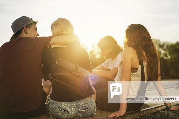 Friends sitting together outdoors at sunset