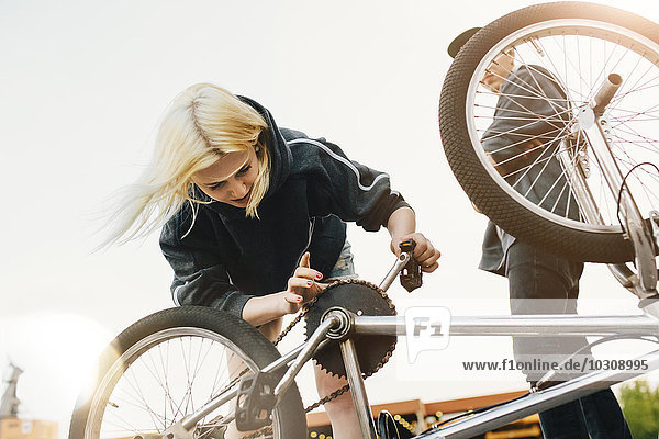 Junge Frau repariert BMX-Fahrrad