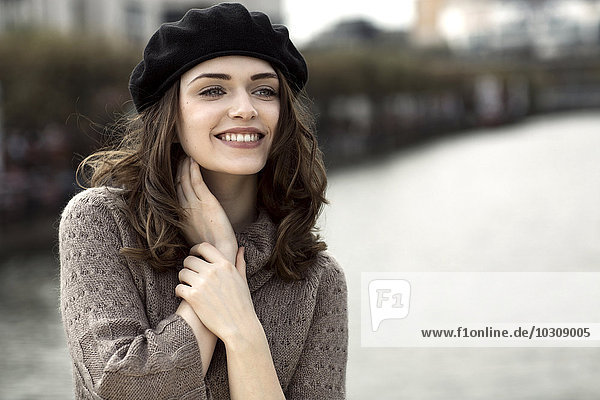 Porträt einer glücklichen jungen Frau mit Baskenmütze und Strickkleid