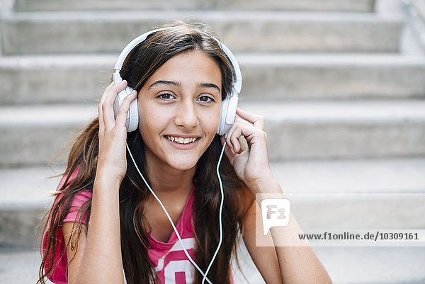 Portrait of smiling teenage girl listening music with headphones