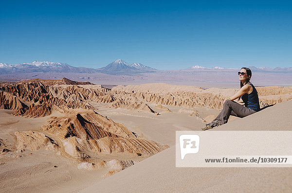Chile  Atacama-Wüste  Frau auf einer Düne sitzend mit Blick auf die Aussicht