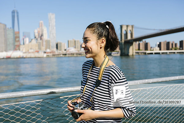 USA  New York City  lächelnde junge Frau mit Kamera