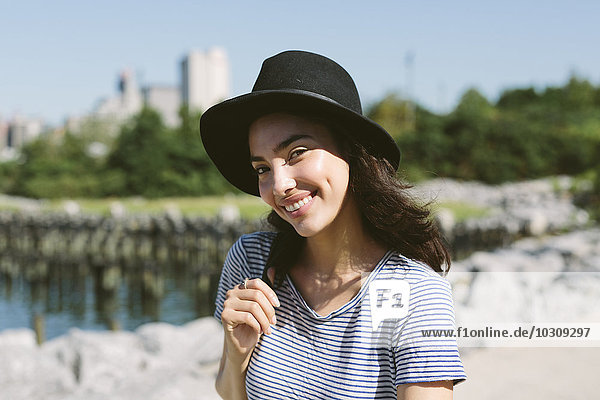 USA  New York City  Portrait einer lächelnden jungen Frau mit schwarzem Hut