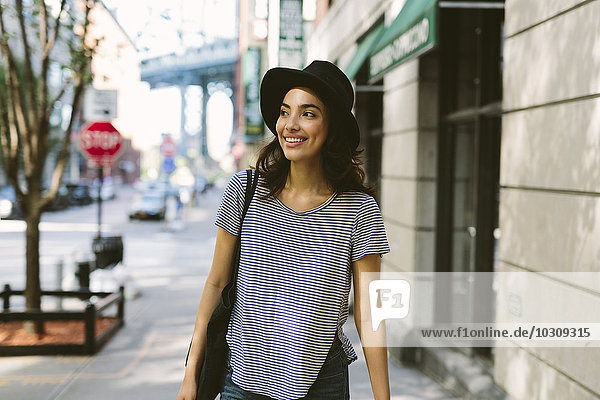 USA  New York City  Portrait einer lächelnden jungen Frau mit schwarzem Hut