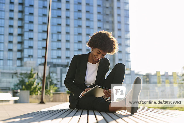 USA  New York City  Geschäftsfrau sitzend auf einer Bank mit digitalem Tablett