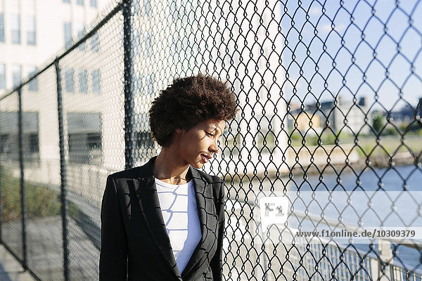 USA  New York City  pensive businesswoman looking through mesh wire fence