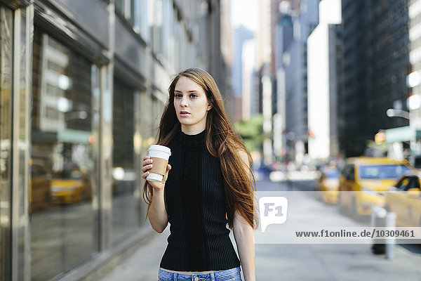 USA  New York City  portrait of young woman with coffee to go