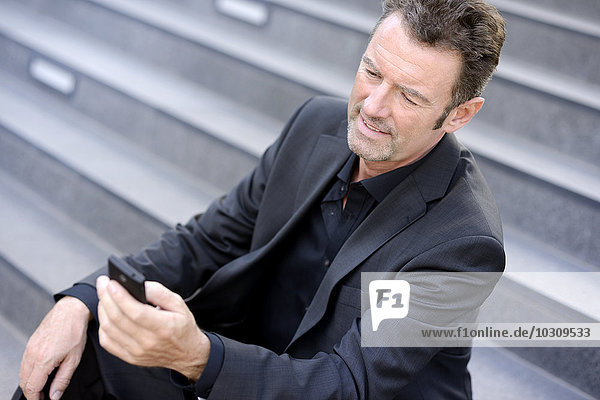Gut gekleideter Geschäftsmann liest SMS