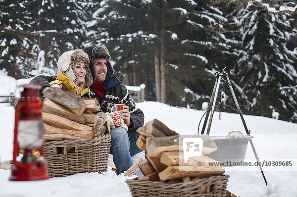 Smiling couple in snow with firewood
