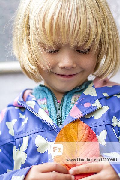 Porträt eines lächelnden kleinen Mädchens mit Herbstblatt