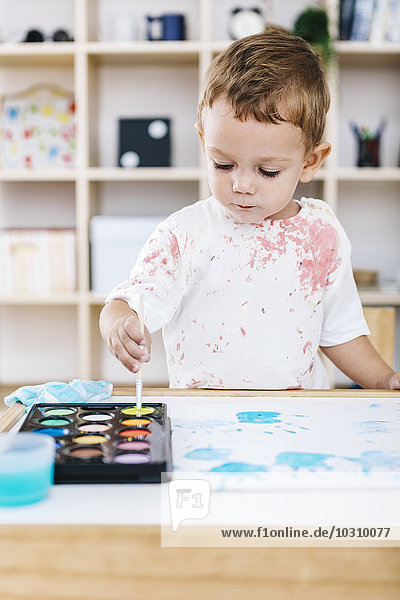 Portrait of little boy painting with watercolours
