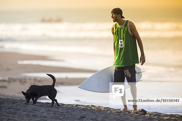 Indonesien  Bali  Surfer und Hund am Strand