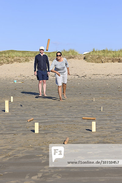 Paar spielt Kubb am Strand