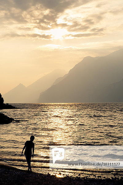 Italy  Veneto  Malcesine  Boy standing at Lake Garda in evening light