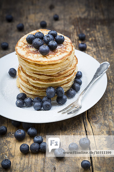 Dish with pile of pancakes  blueberries  sprinkled with icing sugar