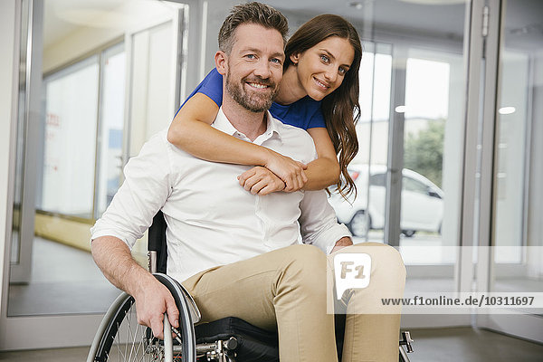 Mann im Rollstuhl mit seiner Freundin  glücklich umarmend