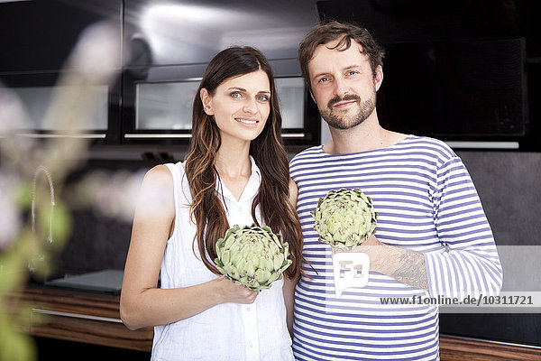 Portrait of couple holding artichokes