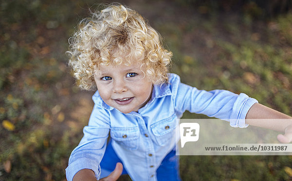 Porträt eines lächelnden blonden kleinen Jungen  der zur Kamera schaut.