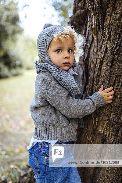 Portrait of little boy wearing autumn fashion besides a tree trunk