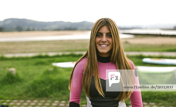 Spanien  Asturien  Villaviciosa  Portrait der lächelnden jungen Frau an der Küste