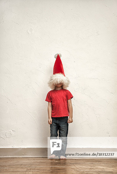 Das Gesicht des kleinen Jungen versteckt sich unter einer überdimensionalen Weihnachtsmütze.