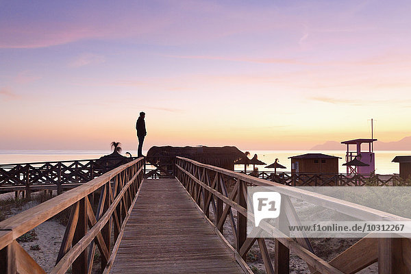 Spain  Balearic Islands  Majorca  one teenage boy standing on a wooden railing watching the sea