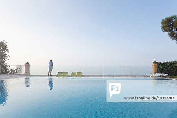 Spanien  Balearen  Mallorca  ein Teenager steht auf einer Glasschiene am Swimmingpool.