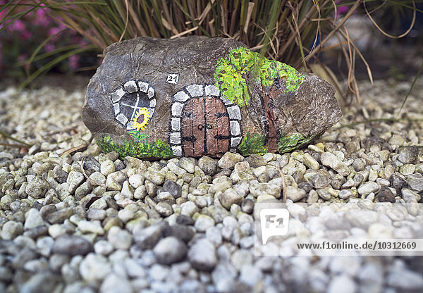 Stein bemalt als kleines Haus im Garten
